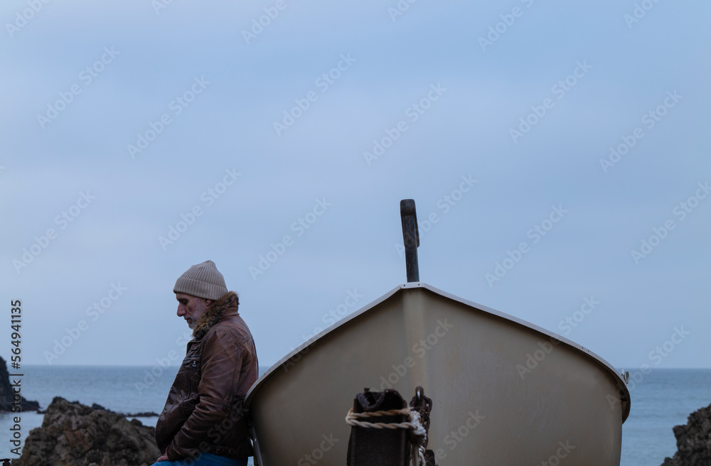 Adult man in leather jacket with a boat against sea and sky. Almeria, Spain