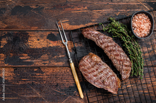 Grilled Sirloin flap or Bavette beef meat steak on a griil with herbs. Wooden background. Top view. Copy space photo