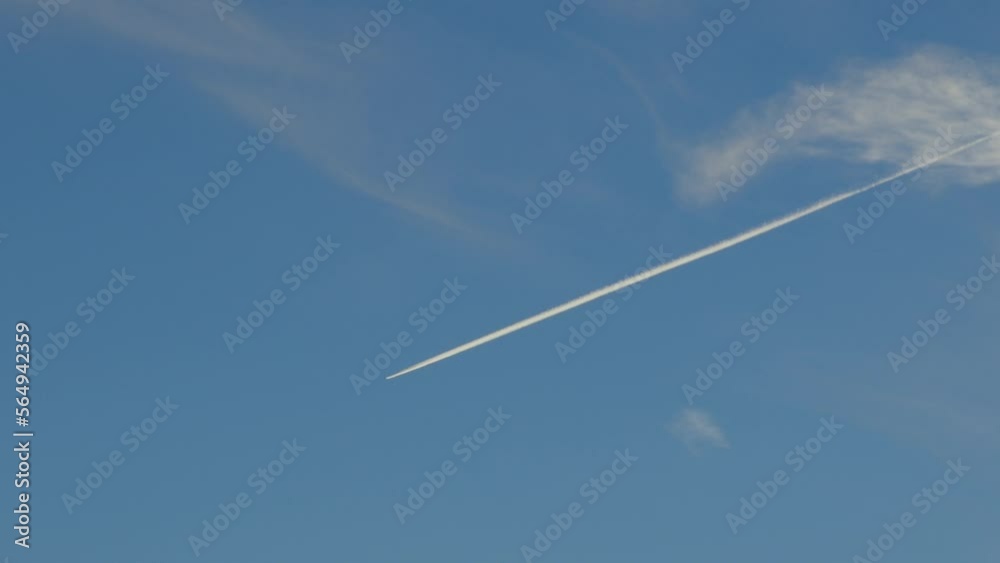Single airplane leaving chemtrail in deep blue sky