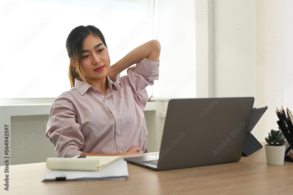 Exhausted female office worker massaging aching neck suffering from pain after computer work Exhausted female office worker massaging aching neck suffering from pain after computer work