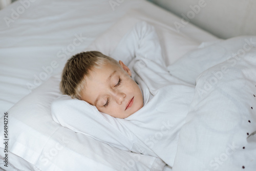 Мальчик спит в кровати . белая постель