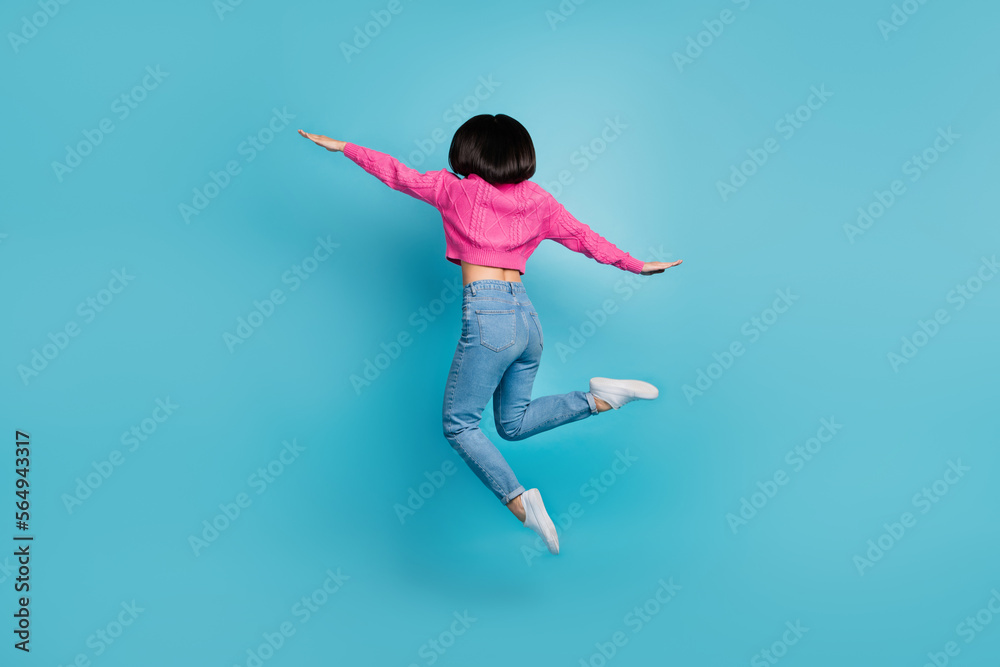 Full length photo of cute cheerful lady wear pink pullover jumping high hands arms wings isolated blue color background
