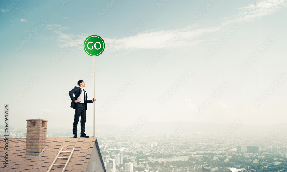 Businessman in suit on house top with ecology concept signboard. Businessman in suit on house top with ecology concept signboard.