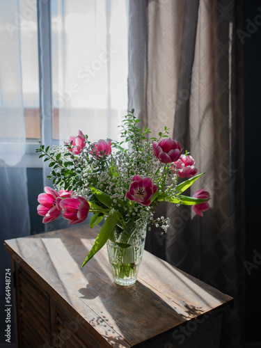 Beautiful bouquet of tulips in glass vase on white marble table. Space for text