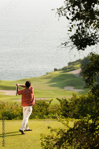 Canvas Print A man plays golf in El Tamarindo with the ocean as the background