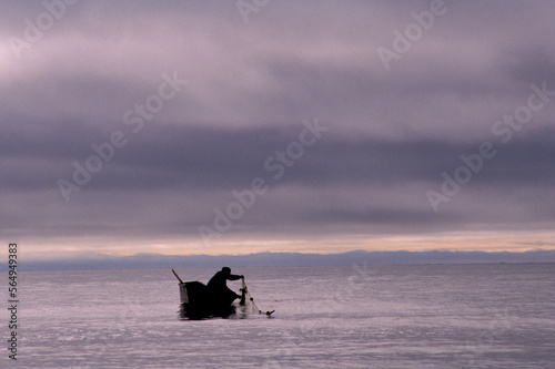 A man in a boat in the Bering Strait, Wales, Alaska, USA. photo