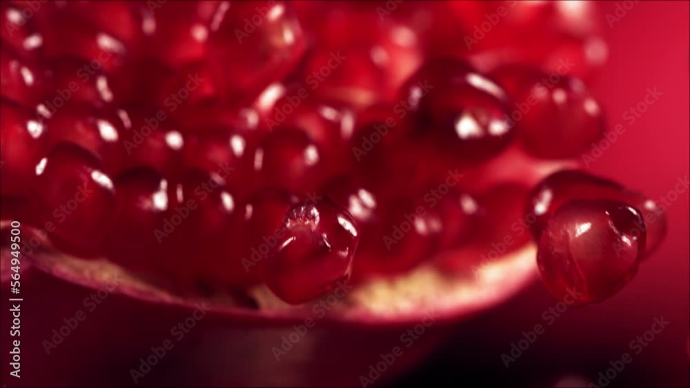 Pomegranate Grains rolls down on surface of broken pomegranate in slow motion