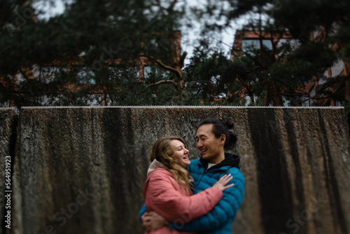 Asian man hugs his whiter wife outdoors photo