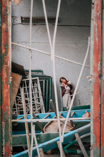 Art work on the theme of the war in Ukraine. A frustrated Ukrainian woman in national dress stands inside a building bombed by the Russian army.