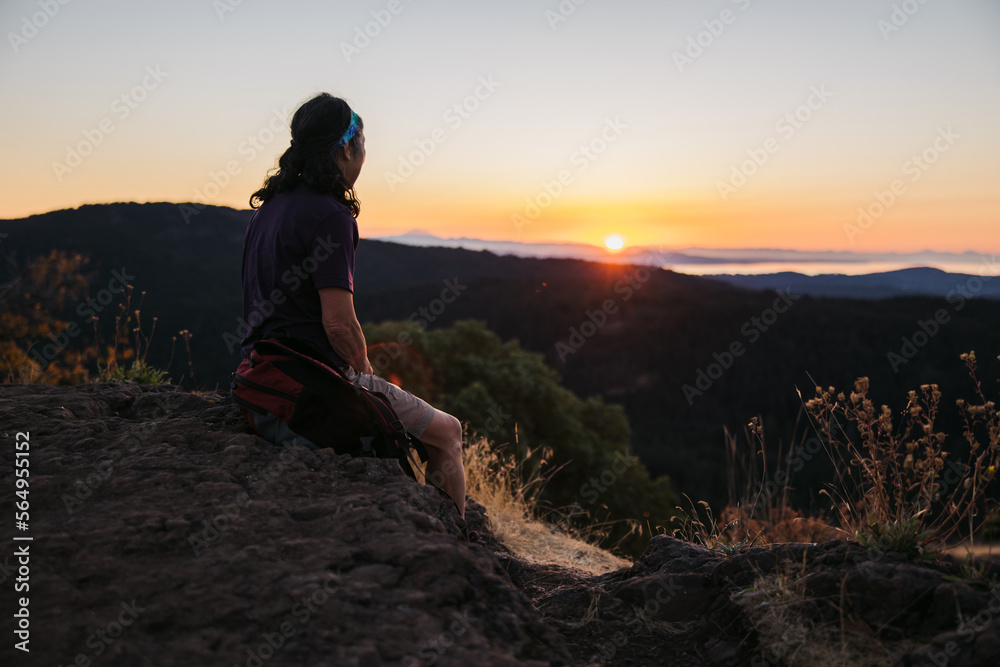 Woman sitting on hilltop watching sunrise. Woman sitting on hilltop watching sunrise.