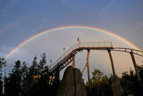Closeup two rainbow in the sky above an amusement park roller coaster