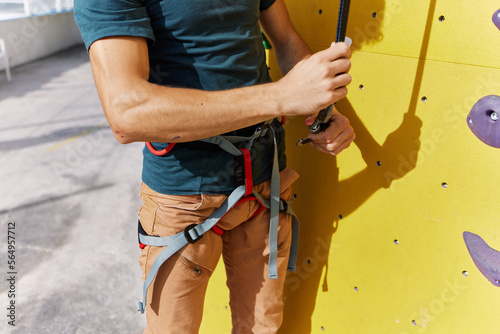 Crop male climber adjusting harness