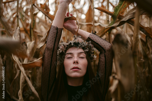 Woman touching dry leaves with raised arms
 photo