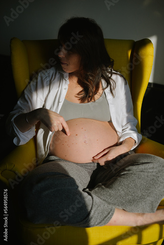 A Nine Months pregnant woman pointing her belly photo