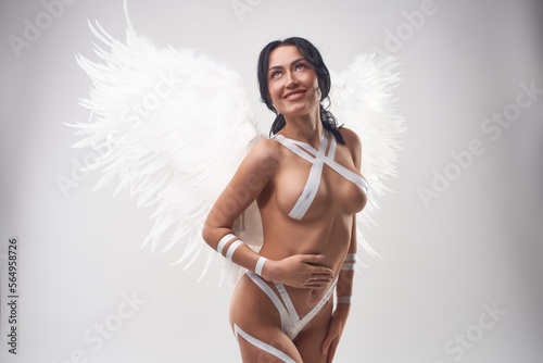 Smiling sexy brunette with angel wings and tape on body