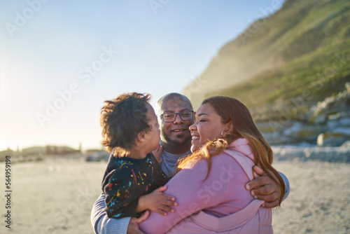Happy parents and son hugging on sunny beach photo