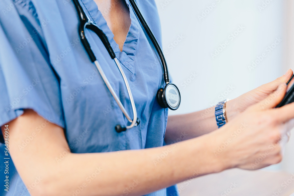 Midsection of female doctor using tablet computer while standing in hospital Midsection of female doctor using tablet computer while standing in hospital