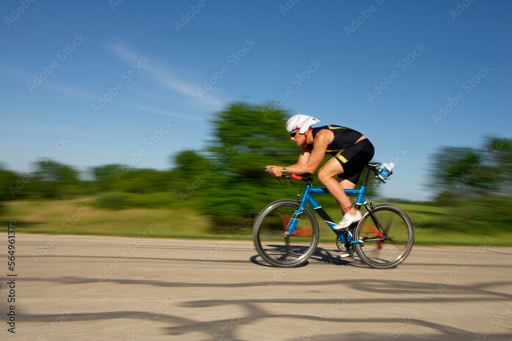 A male athelete training for a triathlon at a lake on a bike. A male athelete training for a triathlon at a lake on a bike.