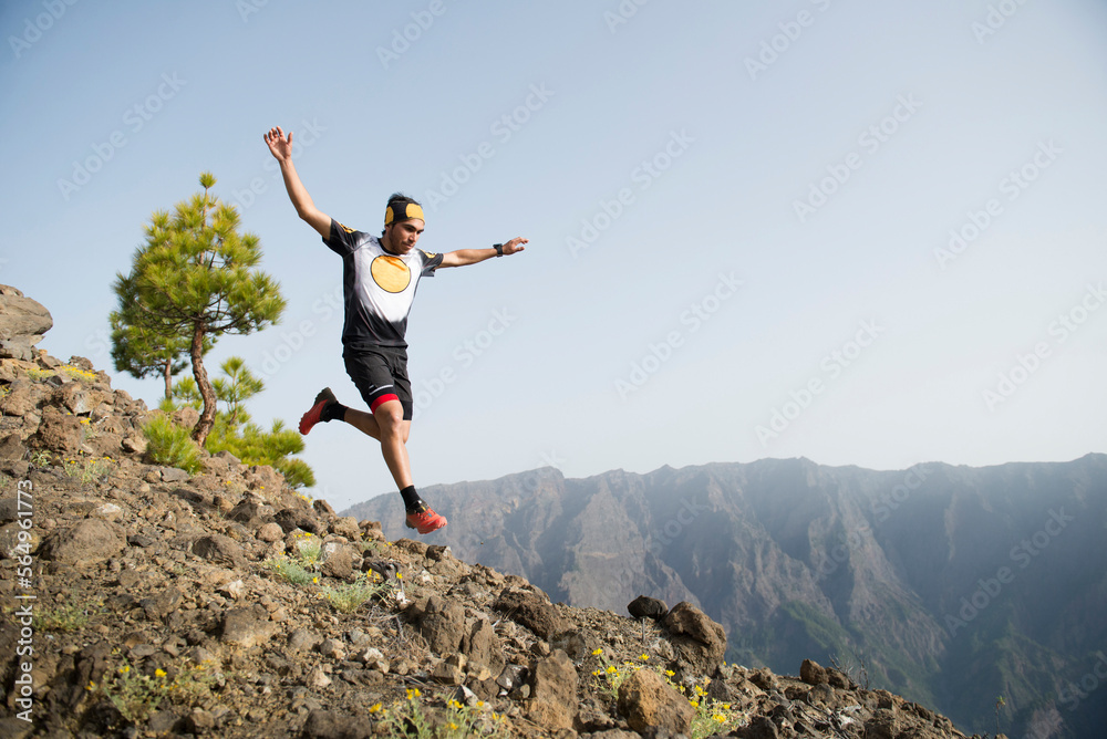 Trail runner jumping with mountains in background, Caldera de Taburiente National Park, Fuencaliente, La Palma, Canary Islands, Spain Trail runner jumping with mountains in background, Caldera de Taburiente National Park, Fuencaliente, La Palma, Canary Islands, Spain