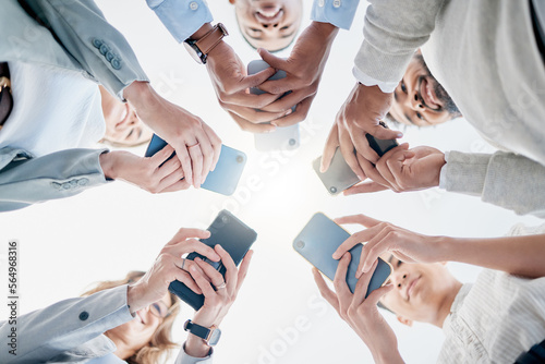 Phone in hands, technology and business people, collaboration and communication in team for company. Chat, internet and community diversity, networking and typing in teamwork circle from below