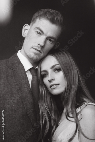 Beautiful stylish and fashionable couple in a suit, dress and coat with gloves on a classic photo shoot in a photo studio and on the street, where they look at each other, hold hands and hug.