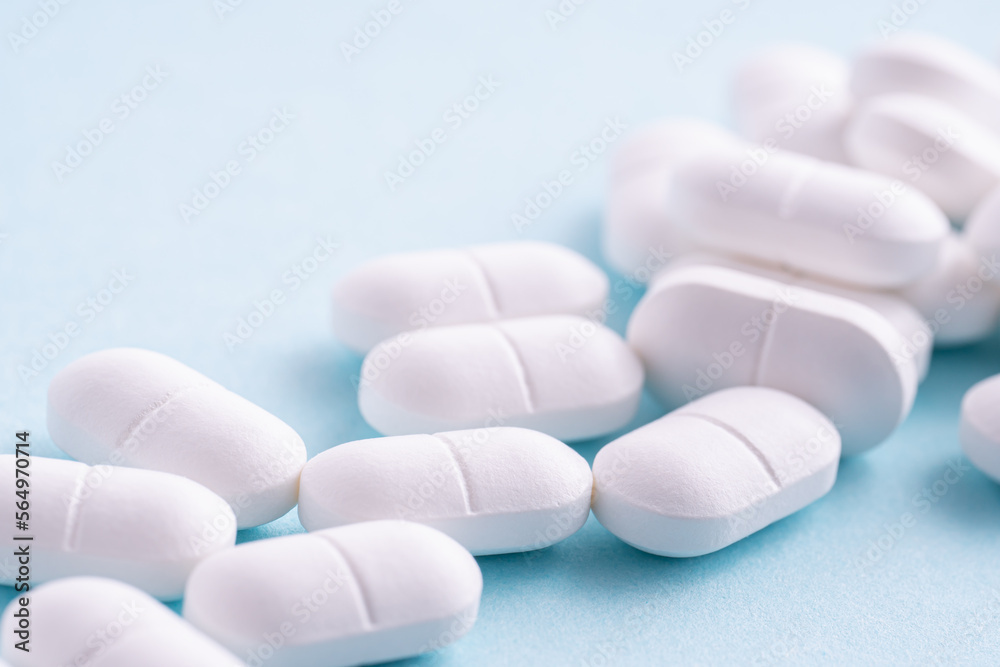 White medicine pills on a blue background.
