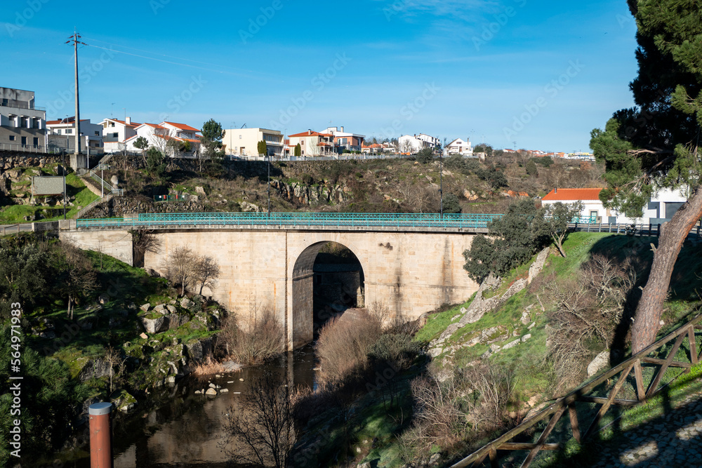 Ponte antiga de pedra sobre um pequeno ribeiro com parte da vila de Miranda do Douro em Trás os Montes, Portugal