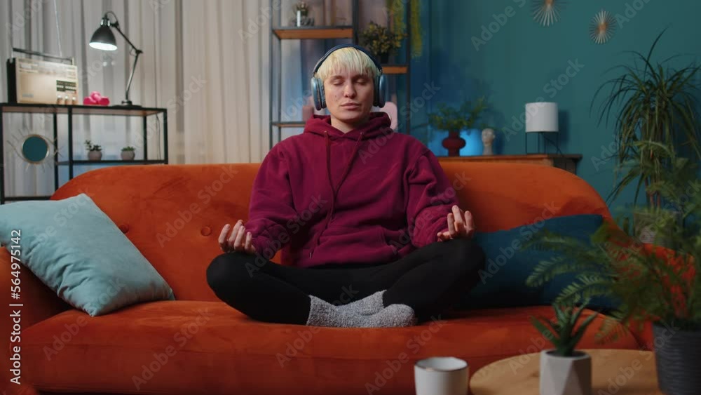 Keep calm down, relax. Woman with short hair at home couch breathes deeply with mudra gesture, eyes closed meditating with concentrated thoughts, peaceful mind, listen music. Girl in evening room Keep calm down, relax. Woman with short hair at home couch breathes deeply with mudra gesture, eyes closed meditating with concentrated thoughts, peaceful mind, listen music. Girl in evening room
