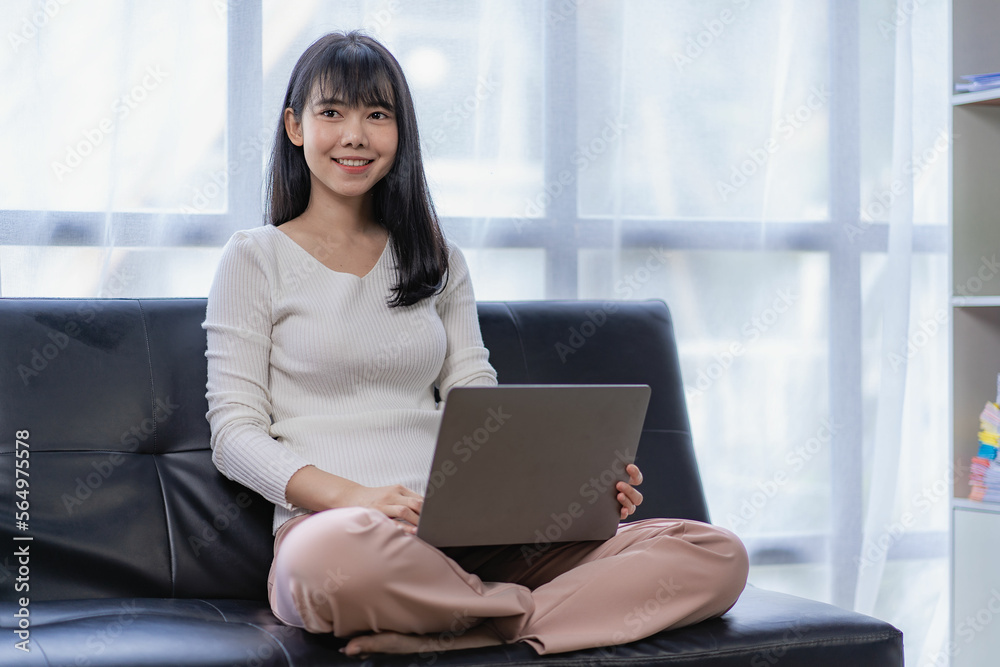 Happy Asian woman sitting on sofa with laptop surfing internet online shopping at home. Happy Asian woman sitting on sofa with laptop surfing internet online shopping at home.