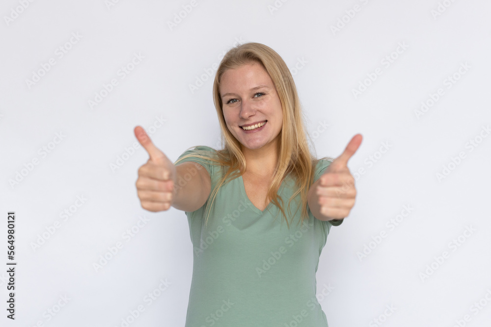 Joyful woman showing thumb up. Young female model smiling showing like gesture with both hands. Portrait, studio shot, support, quality concept Joyful woman showing thumb up. Young female model smiling showing like gesture with both hands. Portrait, studio shot, support, quality concept