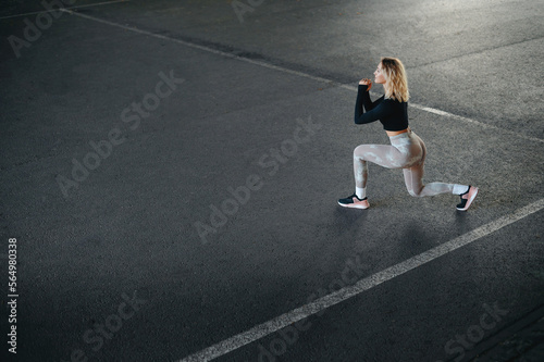 Blonde slim woman in sportswear doing forward lunges exercises