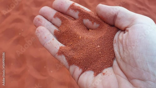 Red sand of Wadi Rum desert running through fingers, close up of a handful of sand in Jordan, Middle East photo