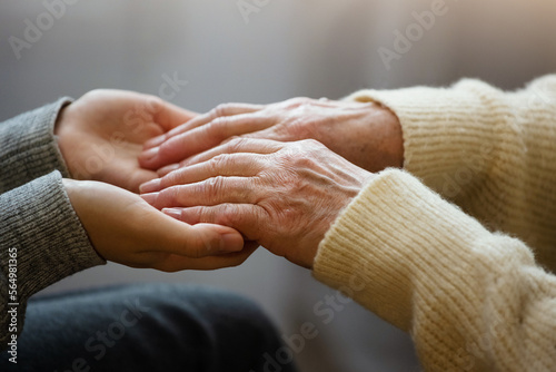 Closeup of hands of old man and a young female hands. Senior man, with caregiver indoors. Concept of health caring for elderly old people, disabled.