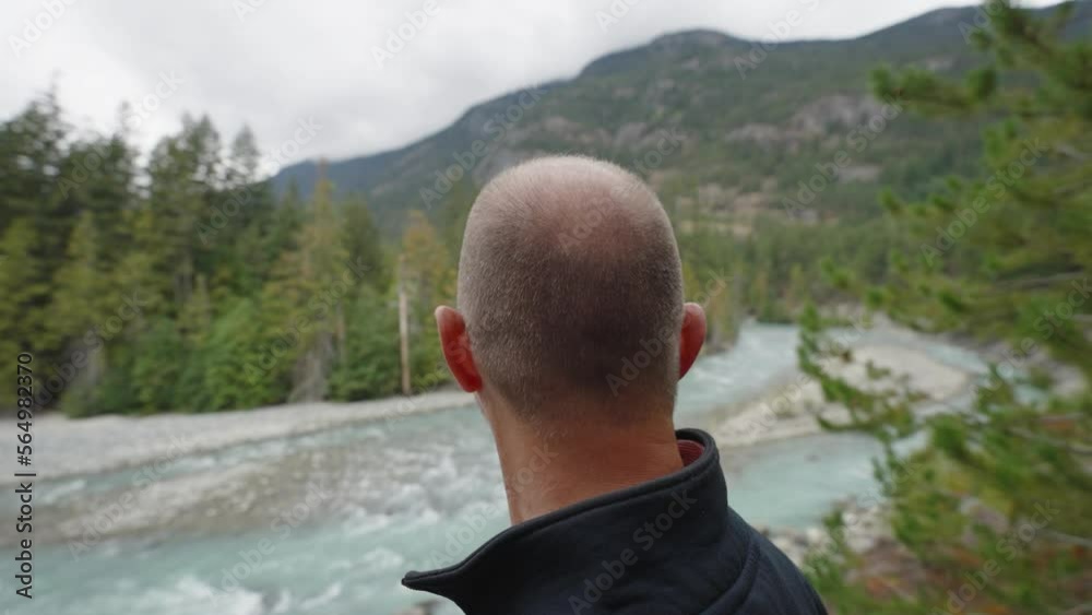 Man looks out over Canadian river view from ridge lookout Man looks out over Canadian river view from ridge lookout
