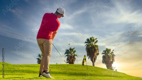 Foto Golfer approaching a golf ball on the golf green with the sun setting at dusk