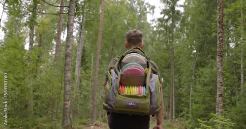 Disc golfer walks on a disc golf course in the forest - medium shot photo