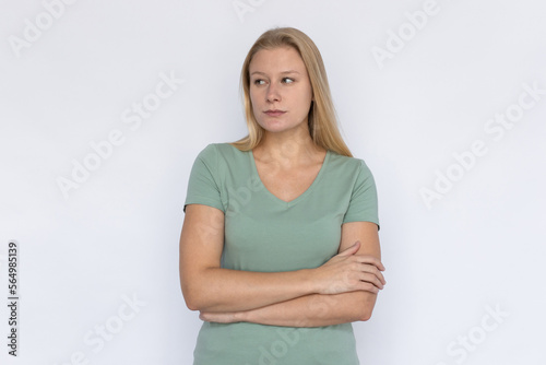 Serious woman with arms crossed. Young female model looking aside. Portrait, studio shot, strength, disappointment concept