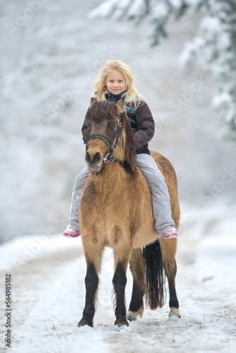 A young girl is riding a horse in winter