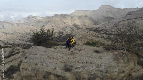 Drone shot, a young gay couple kissing each other while sitting on the mountain photo