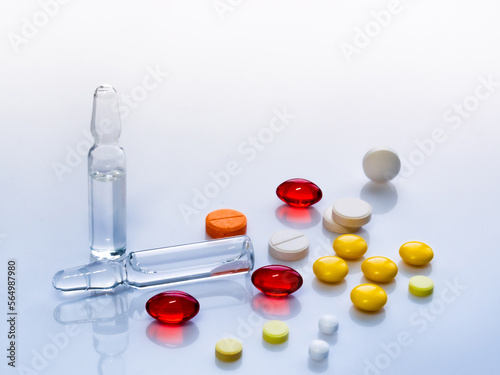multicolored vitamin pills and vaccine ampoules close-up