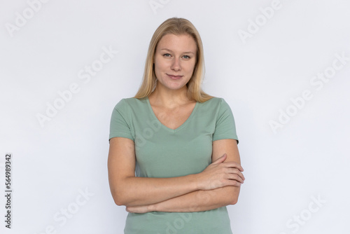 Positive woman with arms crossed. Young female model standing crossing arms and smiling. Portrait, studio shot, confidence concept