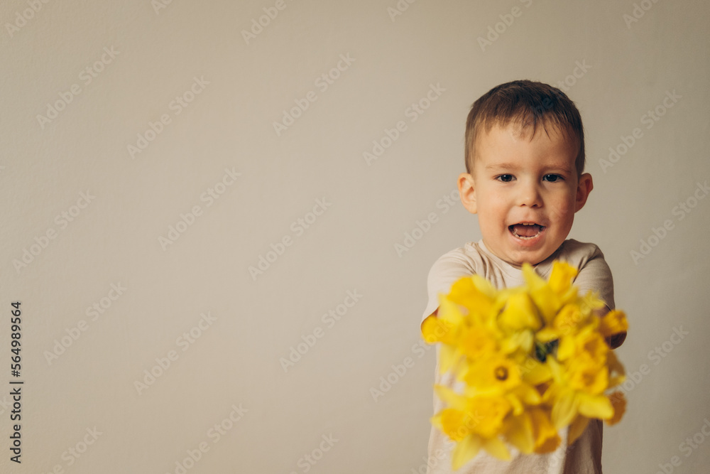 little boy holding and giving bouquet of bright yellow daffodils flowers hiding his face behind it. little boy holding and giving bouquet of bright yellow daffodils flowers hiding his face behind it.
