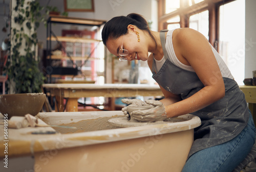 Pottery wheel, workshop and startup business woman manufacturing creative art product with hands. Happy asian potter artist working in clay or ceramics retail industry, studio or class with pride