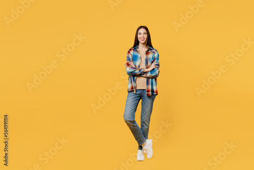 Full body cheerful happy confident young smiling woman wear blue shirt beige t-shirt look camera hold hand crossed folded isolated on plain yellow background studio portrait. People lifestyle concept