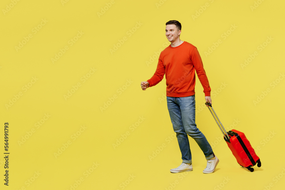 Side view traveler man wear orange casual clothes hold suitcase bag walk go isolated on plain yellow background Tourist travel abroad in free spare time rest getaway. Air flight trip journey concept. Side view traveler man wear orange casual clothes hold suitcase bag walk go isolated on plain yellow background Tourist travel abroad in free spare time rest getaway. Air flight trip journey concept.