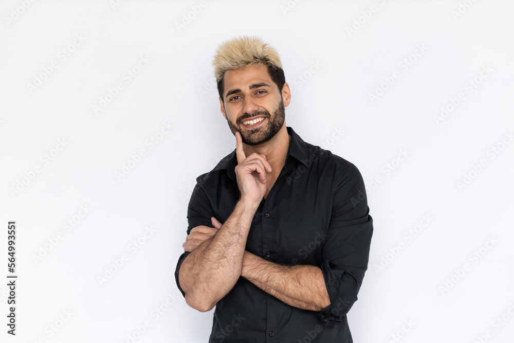 Portrait of cheerful young man looking at camera and smiling over white background. Caucasian guy with stubble and highlighted hair wearing black T-shirt touching chin and thinking. Idea concept Portrait of cheerful young man looking at camera and smiling over white background. Caucasian guy with stubble and highlighted hair wearing black T-shirt touching chin and thinking. Idea concept
