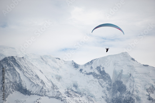 paraglider high in the sky over snowy mountains
