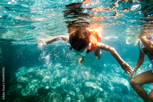 A Boy Snorkels With His Mother In Turquoise Water