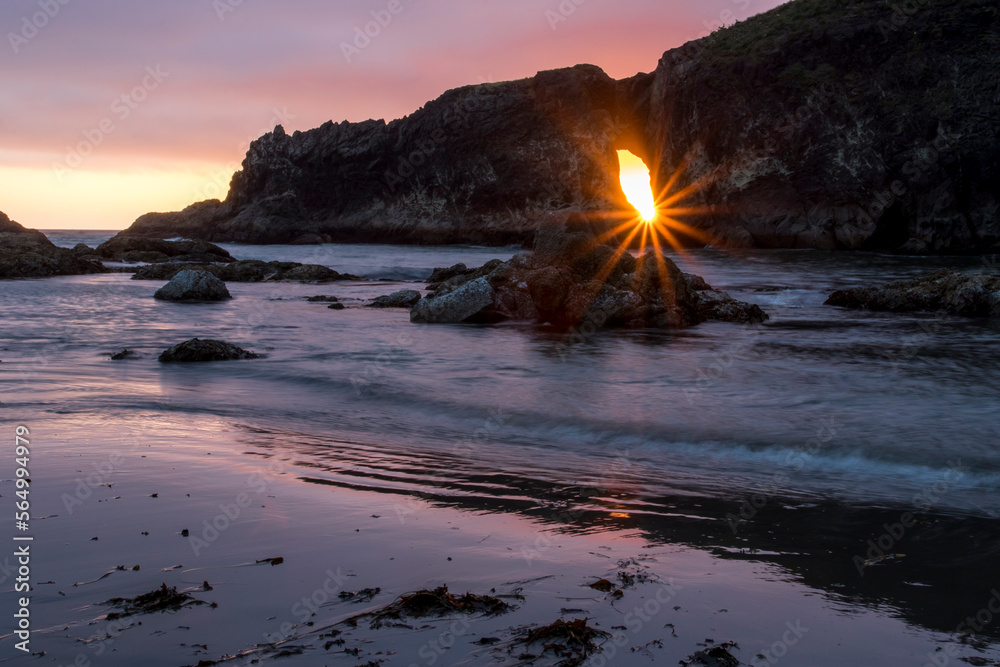 Sun shining through hole in rocky outcrop at Second Beach at sunset, La Bush, Washington State, USA Sun shining through hole in rocky outcrop at Second Beach at sunset, La Bush, Washington State, USA