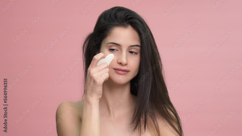 Smiling woman massaging her face with wasa stone in studio Smiling woman massaging her face with wasa stone in studio
